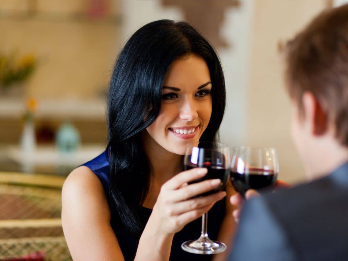 Mulher de cabelos pretos tomando vinho construindo relacionamento com o cliente Mulher de cabelos pretos tomando vinho com um homem. Primeiro encontro também acontece no relacionamento com o cliente e poderá ou não evoluir.