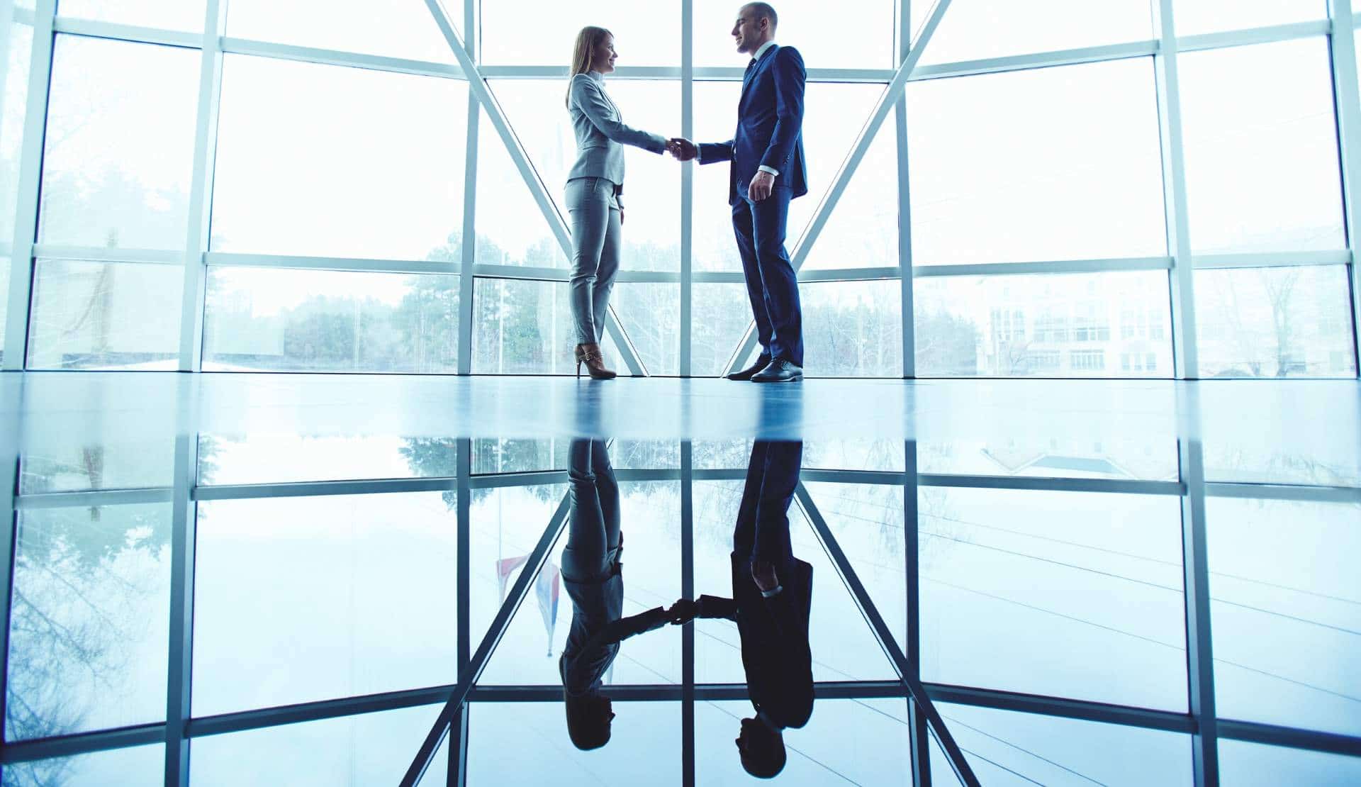 Um aperto de mãos entre um homem e uma mulher em uma atmosfera empresarial sinalizando uma venda B2B bem-sucedida.